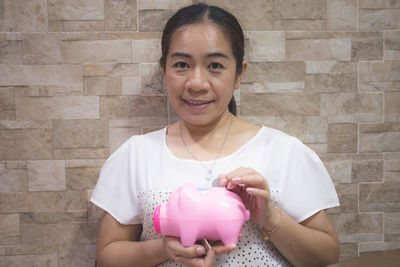 Woman smile putting money in piggy bank