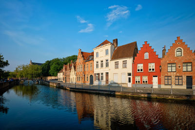 Buildings by river against sky