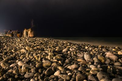 Close-up of pebbles on beach against sky at night