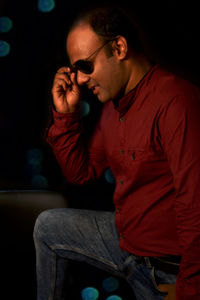 Young man looking away while sitting outdoors