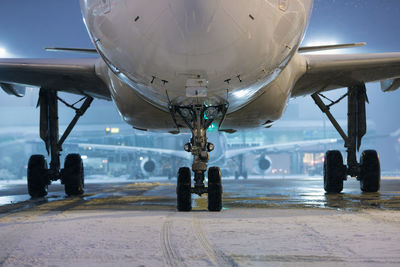 Winter frosty night at airport during snowfall. front view of airplane landing gear.