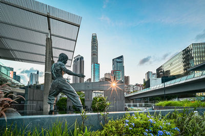 Low angle view of statue against modern buildings in city
