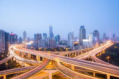 High angle view of light trails on road amidst buildings in city against sky