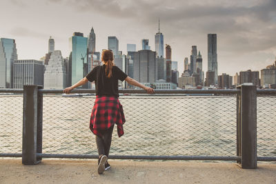Rear view of woman standing by railing against cityscape