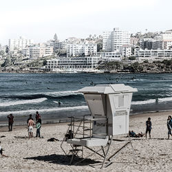 People at beach against sky in city