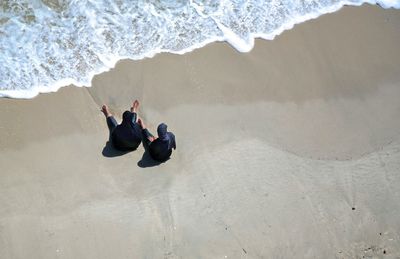 High angle view of carefree women sitting on shore at beach