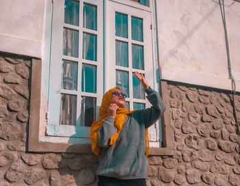 Woman standing by window of building