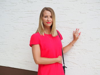 Beautiful young woman standing against wall
