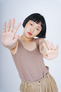 Portrait of young woman standing against white background