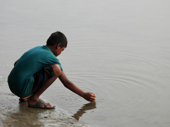 Side view of young man standing in lake