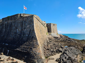 Low angle view of fort on sea against blue sky