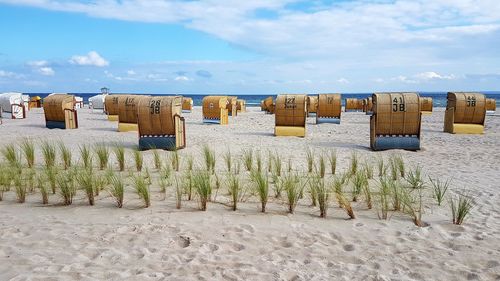 Hooded chairs on beach against sky