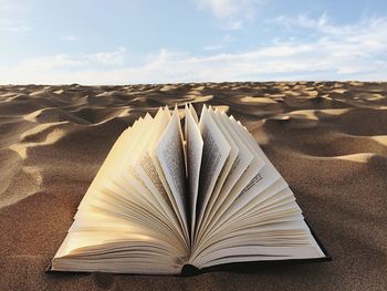 Close-up of open book on sand