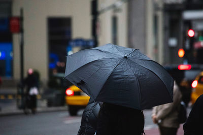 Rear view of person with umbrella in city