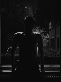 Rear view of silhouette woman standing against trees at night