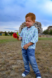 Life style portrait red-haired boy in a park with flowers, cheerful childhood, summer vacation 