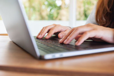 Cropped hands using laptop on table