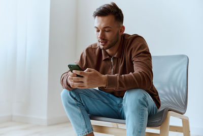 Young man using mobile phone while sitting on sofa at home