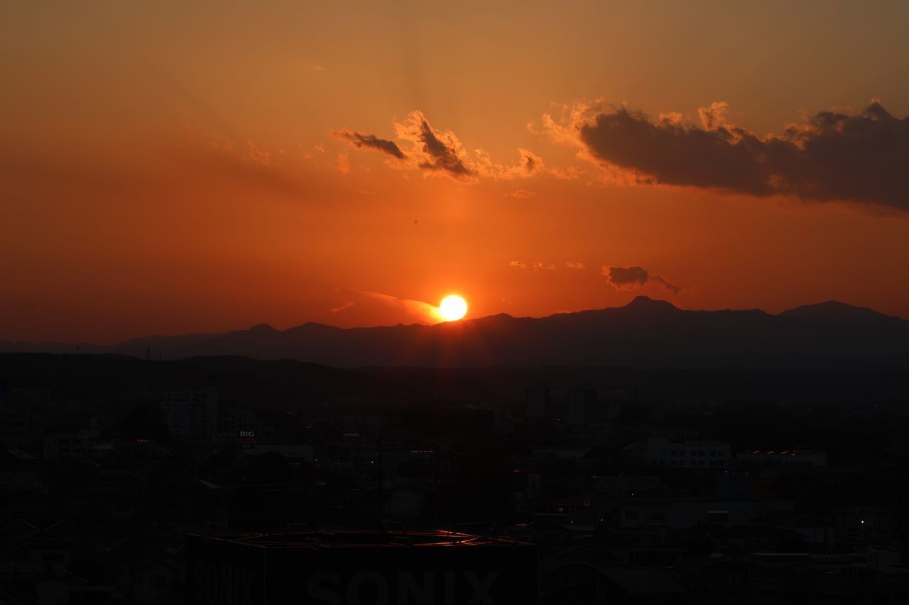 SILHOUETTE CITYSCAPE AGAINST ORANGE SKY