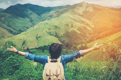 Rear view of woman with arms outstretched on mountains