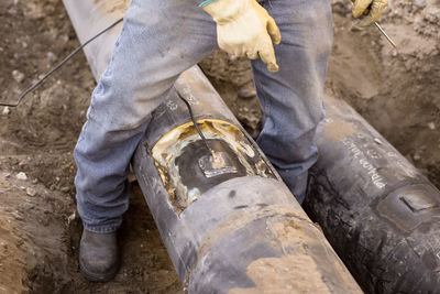 Low section of manual worker standing over metal