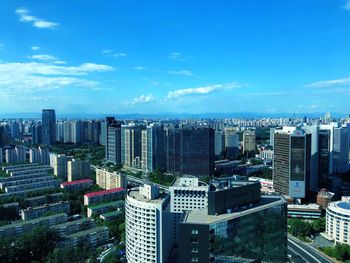 High angle view of buildings in city against blue sky