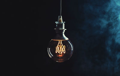 Low angle view of illuminated light bulb against sky at night