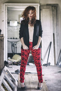 Portrait of woman standing against red wall