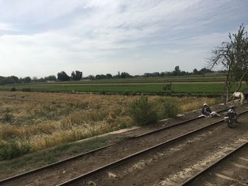 Railroad track amidst field against sky