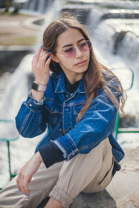Young woman wearing sunglasses looking away while sitting outdoors