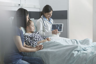 Patient looking at digital tablet held by doctor at clinic