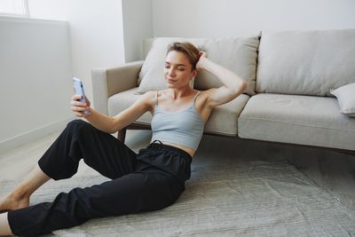 Low section of woman sitting on sofa at home