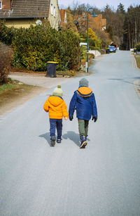 Rear view of boy walking on road