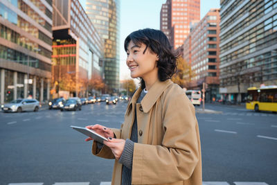 Young woman using mobile phone in city