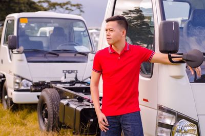 Young man standing by parked vehicle on field