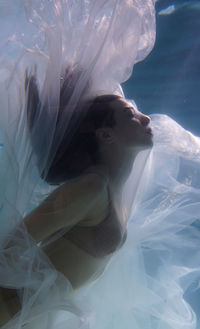 Woman with curtain swimming in pool