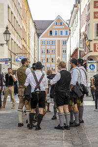 Rear view of people walking on street amidst buildings in city