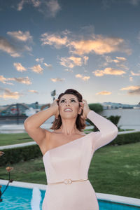 Portrait of a smiling young woman standing against sky