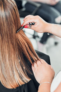 Cropped hands of hairdresser cutting woman hair in salon