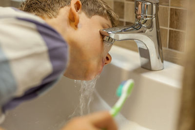 Close-up of boy brushing teeth at bathroom