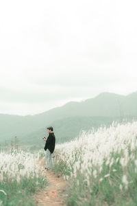 Man sitting on field by mountain against sky
