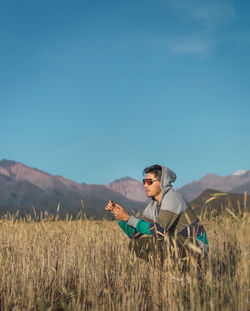 Side view of man standing on field against sky