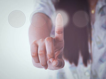 Digital composite image of woman touching button on invisible screen 