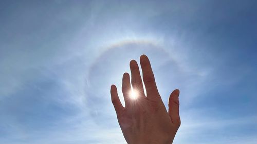 Low angle view of human hand against sky