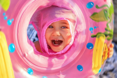 Close-up portrait of cute smiling girl with mouth open holding inflatable ring