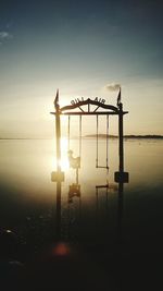 Silhouette lifeguard hut on beach against sky during sunset
