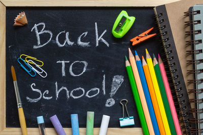 Close-up of back to school text on blackboard with school supplies