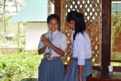 Smiling teenage girl with friend wearing school uniforms