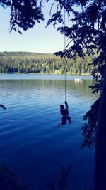 Man swinging on rope over hyalite lake
