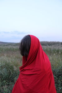 Rear view of woman standing on field against sky